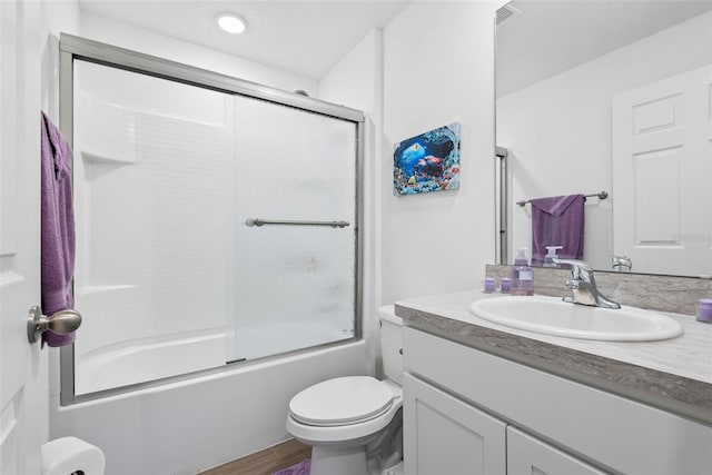 bathroom with enclosed tub / shower combo, vanity, toilet, and wood finished floors