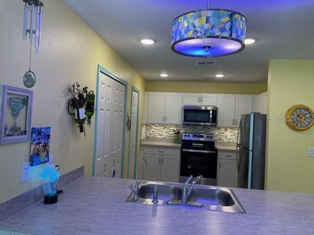 8 Smoke Tree Pl, Palm Coast, FL 32164 - kitchen featuring appliances with stainless steel finishes, a sink, decorative backsplash, white cabinets, and recessed lighting