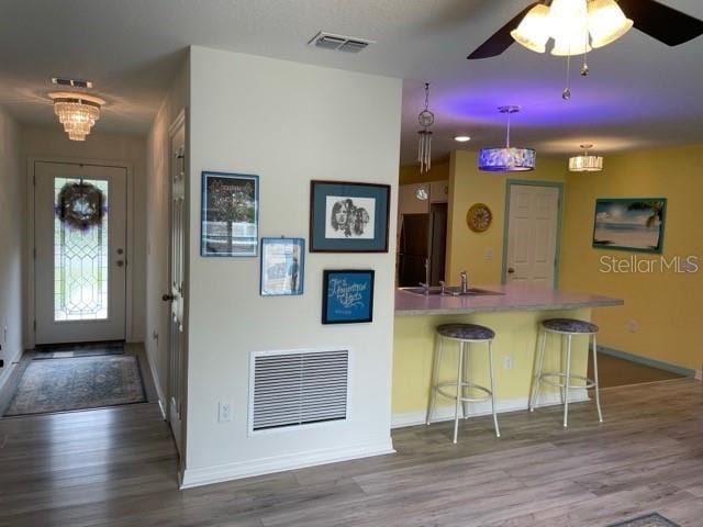 8 Smoke Tree Pl, Palm Coast, FL 32164 - kitchen with wood finished floors, a kitchen breakfast bar, baseboards, freestanding refrigerator, and a ceiling fan