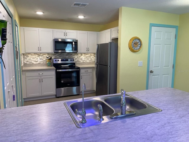 8 Smoke Tree Pl, Palm Coast, FL 32164 - kitchen featuring appliances with stainless steel finishes, a sink, tasteful backsplash, white cabinetry, and light countertops