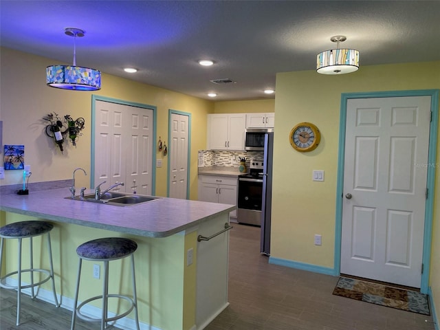 8 Smoke Tree Pl, Palm Coast, FL 32164 - kitchen with appliances with stainless steel finishes, white cabinetry, a kitchen bar, a peninsula, and baseboards