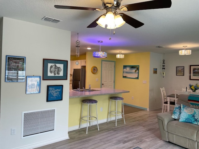 8 Smoke Tree Pl, Palm Coast, FL 32164 - kitchen with a sink, freestanding refrigerator, a breakfast bar, and wood finished floors