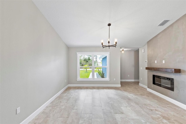 unfurnished living room featuring a glass covered fireplace, visible vents, a notable chandelier, and baseboards