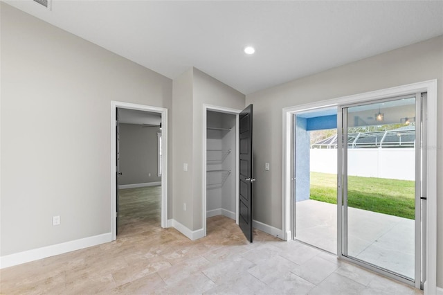 interior space featuring lofted ceiling, baseboards, access to outside, a closet, and a walk in closet