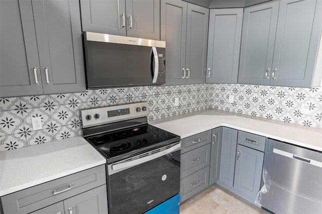 kitchen with stainless steel appliances, tasteful backsplash, and gray cabinets