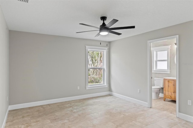 unfurnished bedroom featuring ceiling fan, a textured ceiling, baseboards, and ensuite bathroom