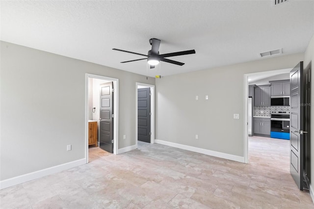 unfurnished bedroom with refrigerator, visible vents, a textured ceiling, ensuite bath, and baseboards