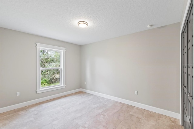 spare room with a textured ceiling and baseboards