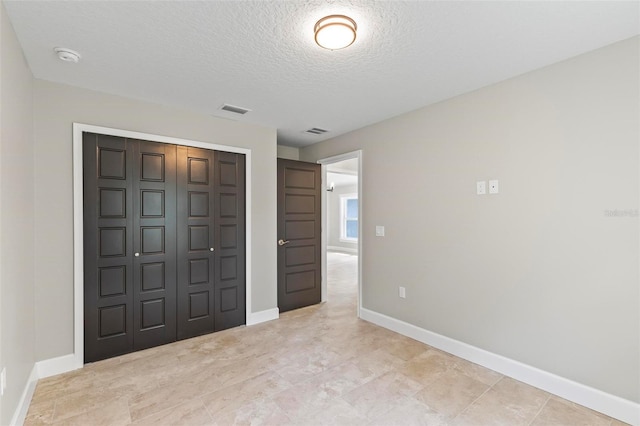 unfurnished bedroom with baseboards, a textured ceiling, visible vents, and a closet