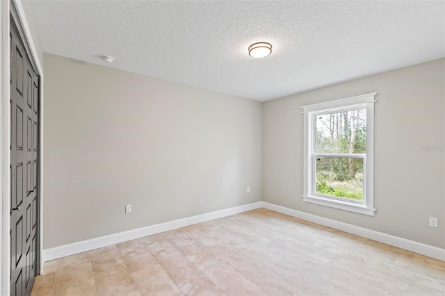 spare room with a textured ceiling and baseboards