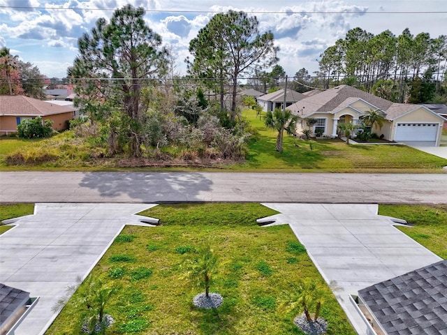 view of yard featuring driveway, an attached garage, and a residential view