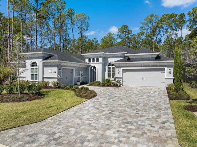 prairie-style home featuring a front yard, decorative driveway, an attached garage, and stucco siding