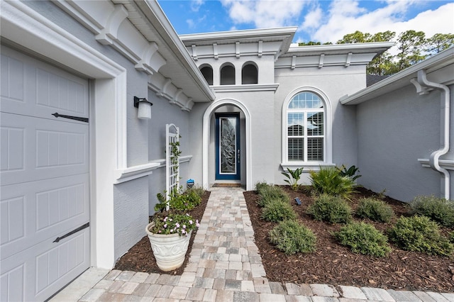 entrance to property featuring a garage and stucco siding