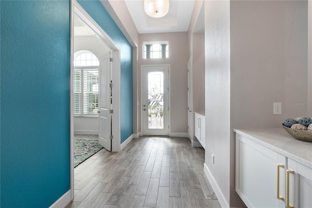 entrance foyer featuring a textured wall, light wood-type flooring, plenty of natural light, and baseboards