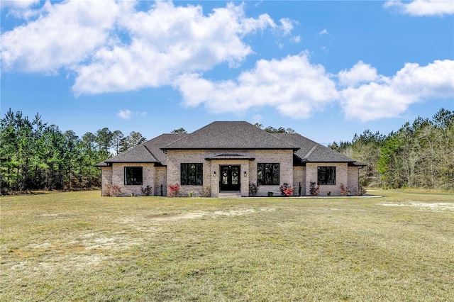 view of front of house with brick siding, roof with shingles, and a front yard