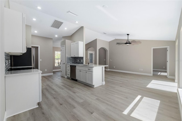 kitchen featuring visible vents, white cabinets, dishwasher, vaulted ceiling, and light countertops