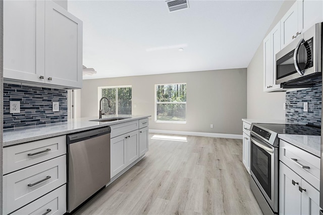 kitchen featuring baseboards, visible vents, light wood-style flooring, appliances with stainless steel finishes, and a sink