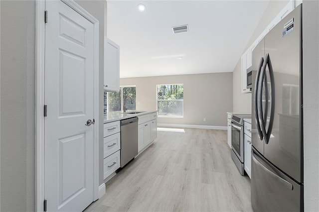 kitchen with visible vents, light wood-style flooring, stainless steel appliances, white cabinetry, and a sink