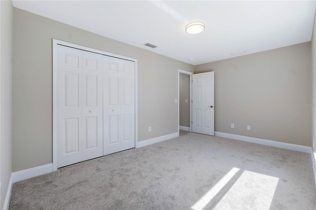 unfurnished bedroom with a closet, carpet, visible vents, and baseboards