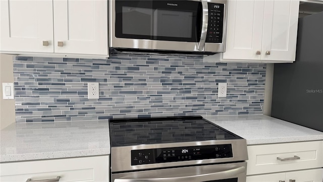 kitchen featuring appliances with stainless steel finishes, white cabinets, backsplash, and light stone countertops