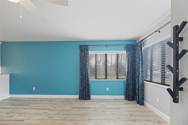 spare room featuring baseboards, a ceiling fan, and light wood-style floors