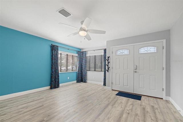 foyer entrance with light wood finished floors, baseboards, visible vents, and a ceiling fan