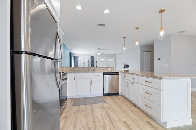 kitchen featuring stainless steel appliances, a peninsula, visible vents, white cabinets, and hanging light fixtures