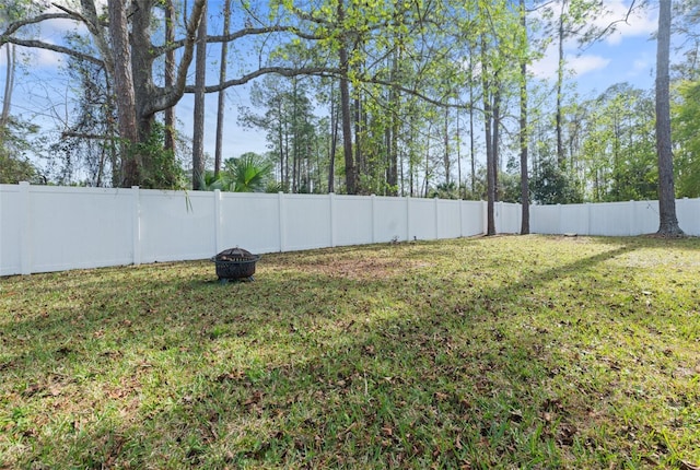 view of yard with a fenced backyard and a fire pit