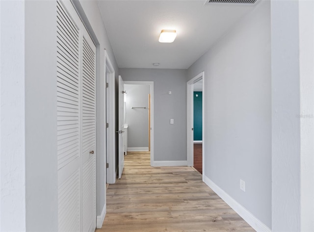 hallway featuring baseboards, visible vents, and light wood-style floors