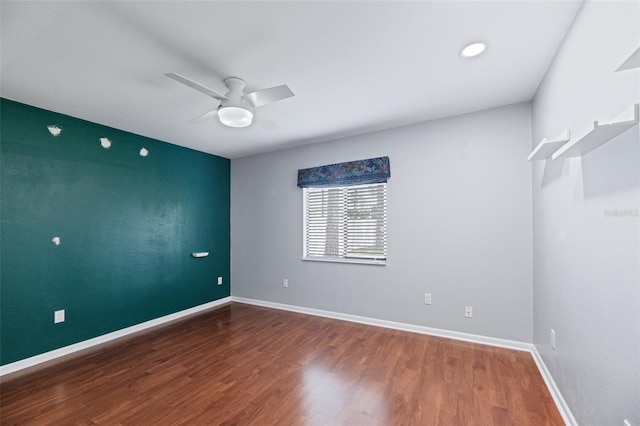 empty room featuring ceiling fan, baseboards, and wood finished floors