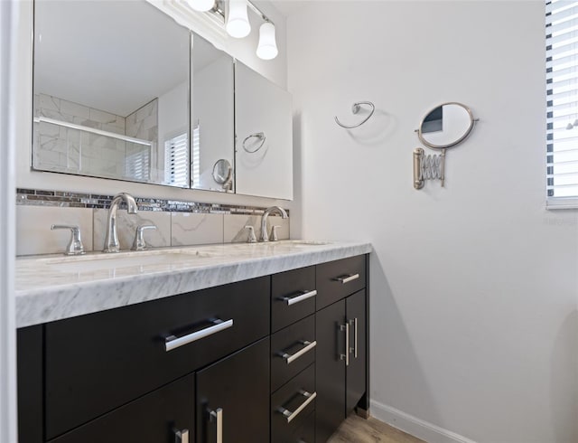 bathroom featuring double vanity, baseboards, a sink, a shower stall, and backsplash