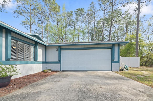 garage with fence and concrete driveway