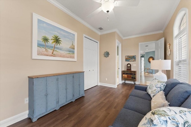 living area with dark wood-type flooring, a ceiling fan, baseboards, and ornamental molding