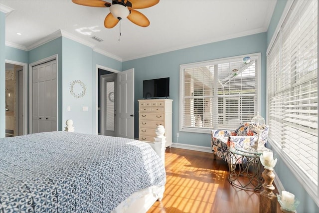 bedroom featuring baseboards, wood finished floors, visible vents, and ornamental molding