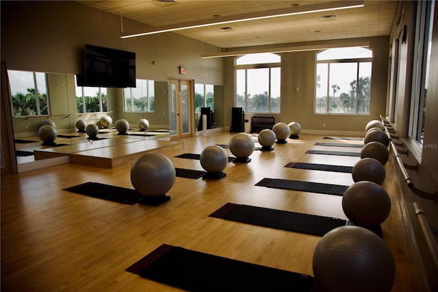 exercise room with visible vents, wood finished floors, baseboards, and a drop ceiling