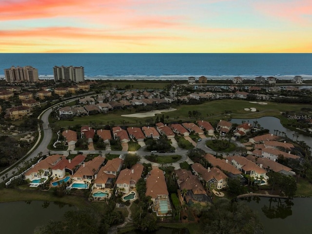 aerial view at dusk featuring a residential view and a water view