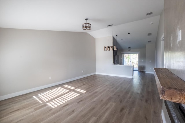 interior space featuring visible vents, vaulted ceiling, baseboards, and wood finished floors