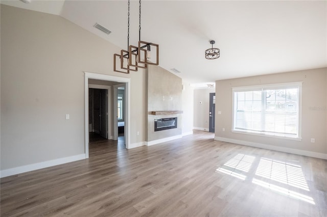 unfurnished living room with a fireplace, visible vents, light wood-style flooring, vaulted ceiling, and baseboards