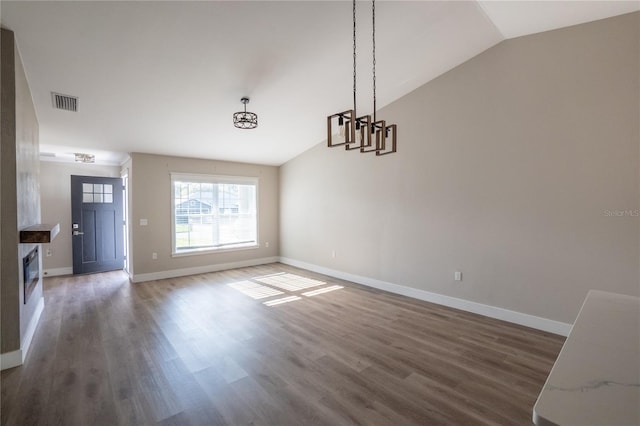 unfurnished dining area with vaulted ceiling, wood finished floors, visible vents, and baseboards