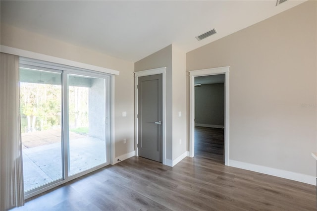 empty room featuring lofted ceiling, baseboards, visible vents, and wood finished floors