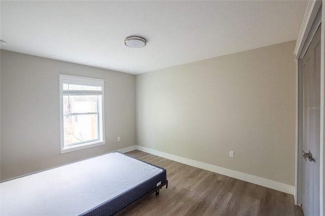 bedroom with a closet, baseboards, and wood finished floors