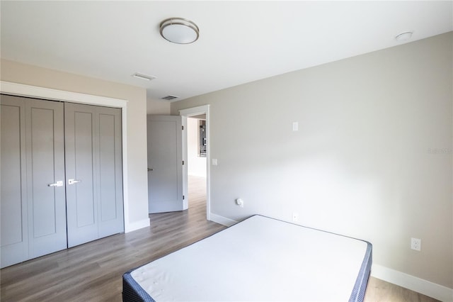 bedroom featuring a closet, baseboards, visible vents, and light wood finished floors