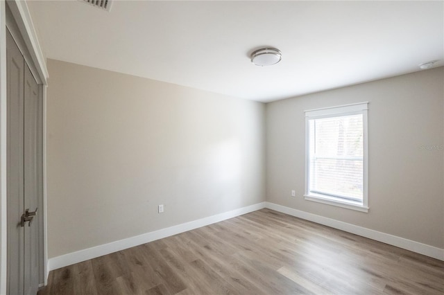 unfurnished bedroom featuring light wood-style floors, baseboards, and a closet