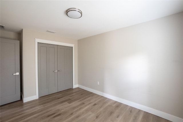 unfurnished bedroom with light wood finished floors, baseboards, and a closet