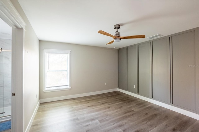 spare room with ceiling fan, wood finished floors, visible vents, and baseboards