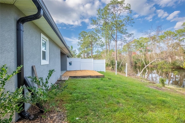 view of yard with fence and a deck with water view