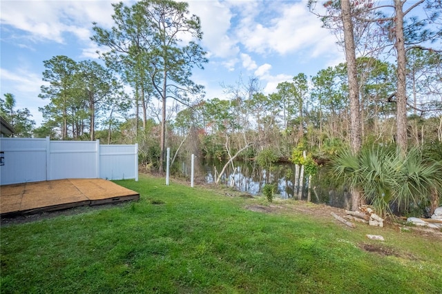 view of yard featuring fence and a deck with water view