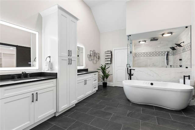 bathroom with lofted ceiling, a sink, a freestanding bath, a shower stall, and two vanities