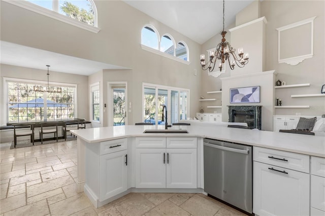 kitchen with a chandelier, stainless steel dishwasher, a sink, and stone tile floors