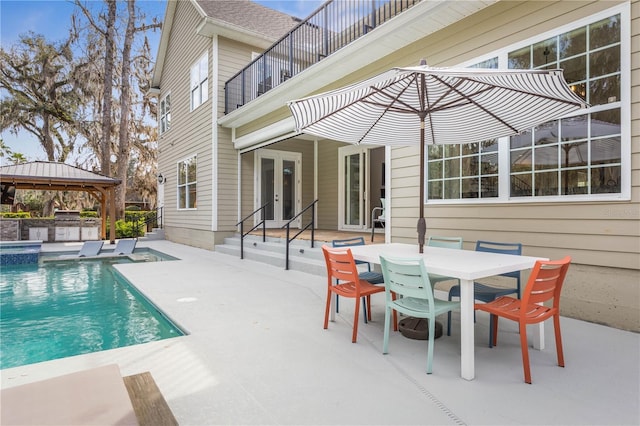 view of pool with a gazebo, exterior kitchen, french doors, outdoor dining space, and a patio area